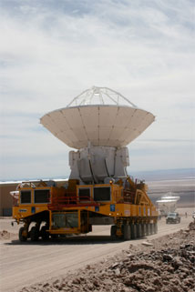 Figure 5: ALMA transporter Otto moves Melco antenna No 4 from the contractor area to the OSF Technical Building area.  Vertex Antennas No 2 and No 1 are also visible (background right).  This was the first move of an antenna by Otto, and the first move of a Melco antenna; the test before the AAER Committee went flawlessly.